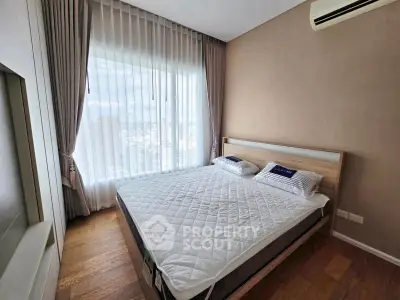 Modern bedroom with large window and wooden flooring in a stylish apartment.
