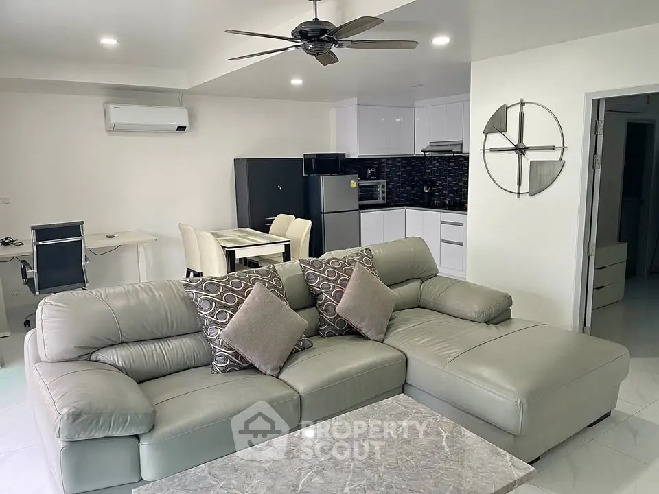 Modern living room with sleek furniture and open kitchen layout in a stylish apartment.