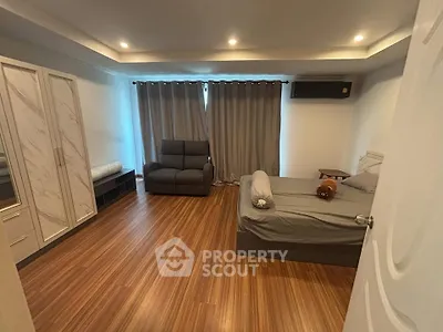 Spacious bedroom with modern decor and wooden flooring, featuring a cozy bed and ample storage.