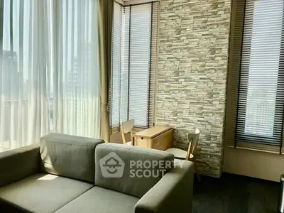 Modern living room with large windows and stylish stone accent wall in urban apartment.