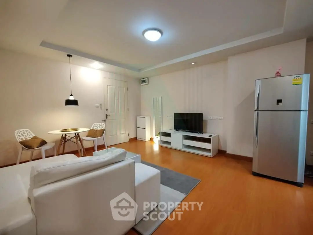 Modern living room with sleek furniture and stainless steel fridge, perfect for urban living.