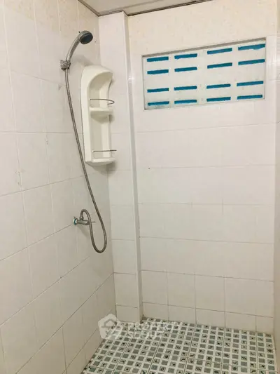 Minimalist bathroom with tiled walls and floor featuring a showerhead and built-in shelf.