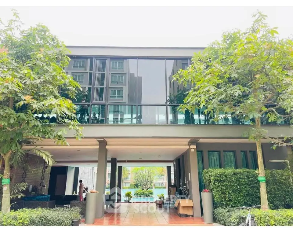 Modern building exterior with lush greenery and large glass windows, showcasing contemporary architecture.