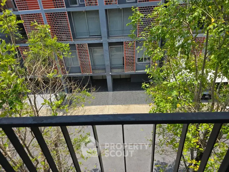 Modern apartment building exterior with lush greenery and balcony view.