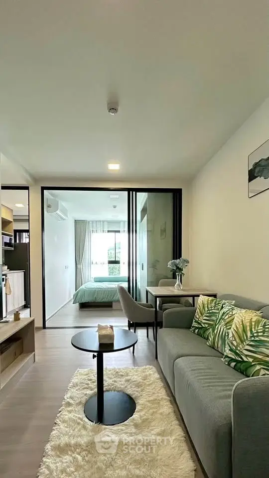 Modern open-plan living room with cozy sofa and stylish decor leading to a bright bedroom.