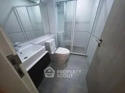 Modern bathroom with sleek fixtures and glass shower enclosure in a contemporary apartment.