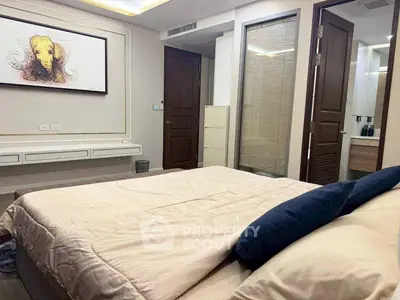 Elegant bedroom with modern decor and stylish artwork, featuring a cozy bed and sleek wooden doors.