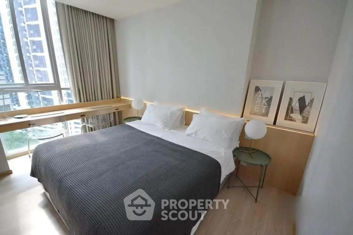 Modern bedroom with large window and stylish decor in urban apartment.