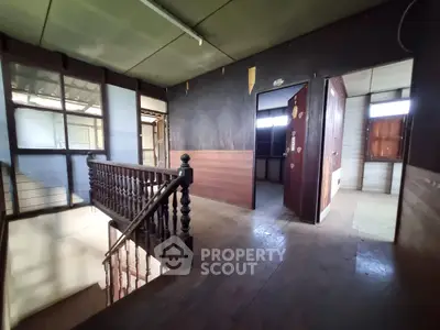 Spacious interior with wooden staircase and vintage charm, ideal for renovation.