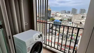 High-rise apartment balcony with city view and washing machine.