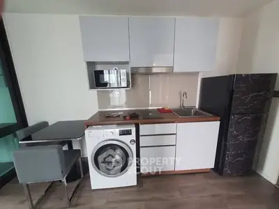 Modern compact kitchen with washing machine and sleek appliances in a stylish apartment.