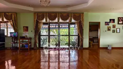 Spacious living room with elegant curtains and polished wooden floors.