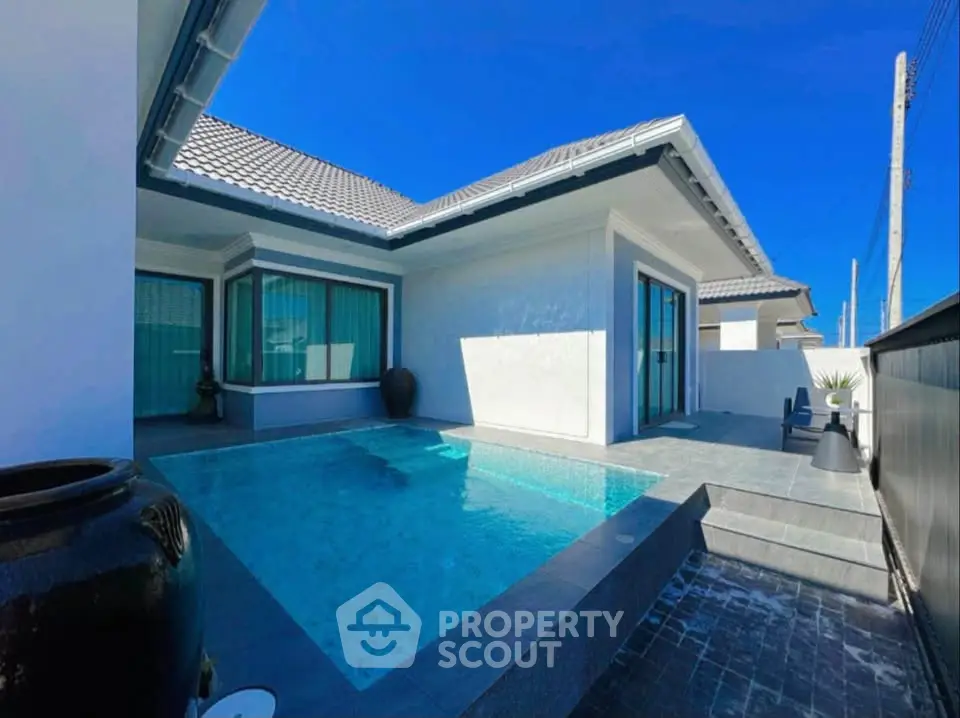 Luxurious modern villa with private pool and sleek exterior design under clear blue sky.