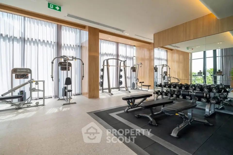 Luxurious gym with modern equipment and floor-to-ceiling windows in upscale building.