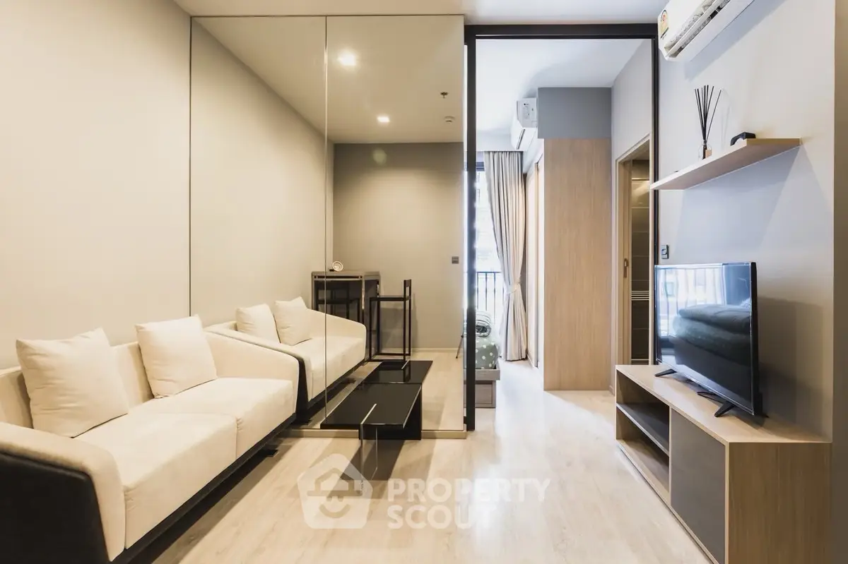 Modern living room with sleek design, featuring a comfortable sofa, wall-mounted TV, and mirrored wall for spacious feel.