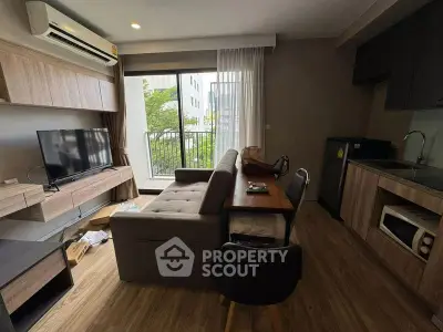 Modern living room with balcony view, featuring stylish furniture and open kitchen layout.