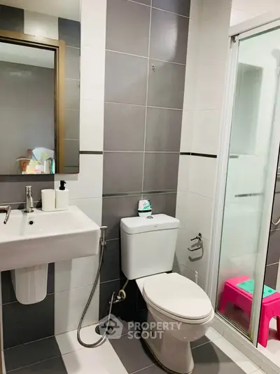 Modern bathroom with sleek fixtures and glass shower enclosure in contemporary apartment.