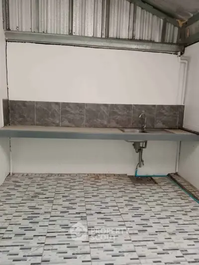 Simple kitchen area with tiled floor and basic sink setup