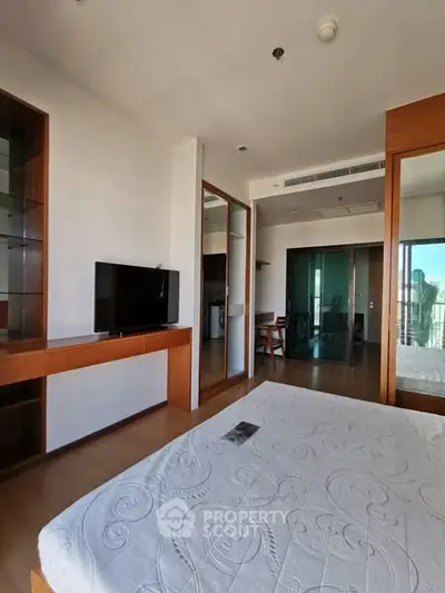Spacious bedroom with modern decor and large windows offering natural light.