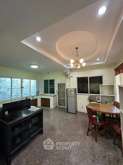 Spacious living room with dining area and modern lighting, featuring large windows and a cozy atmosphere.