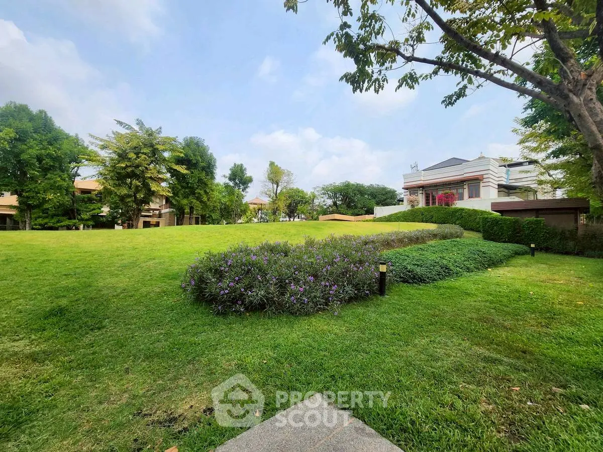 Spacious green garden with modern house in the background, perfect for outdoor activities.