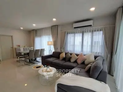 Spacious modern living room with elegant decor and dining area, featuring plush sofa and stylish lighting.