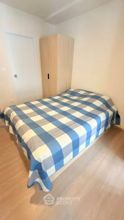 Cozy bedroom with checkered bedding and wooden wardrobe, perfect for a comfortable living space.