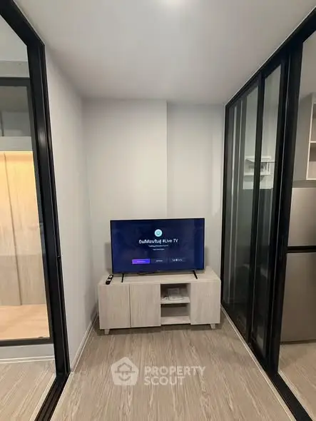 Modern living room with sleek TV setup and glass sliding doors in a stylish apartment.