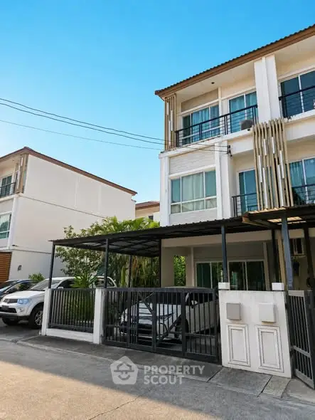 Modern three-story townhouse with carport and gated entrance in a suburban neighborhood.