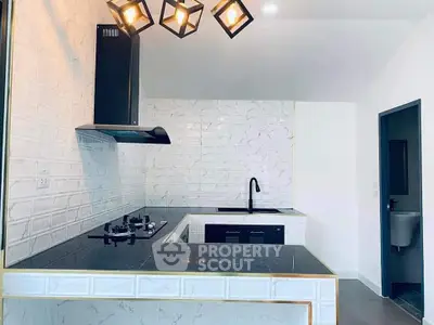 Modern kitchen with sleek black countertops and stylish lighting fixtures.