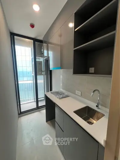 Modern kitchen with sleek cabinetry and balcony view in a contemporary apartment.
