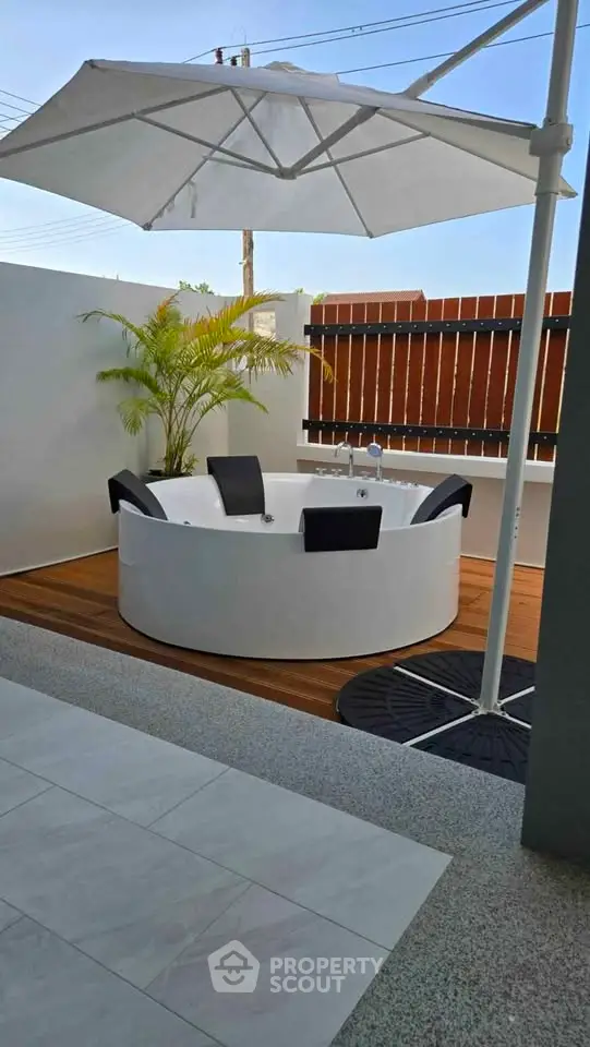 Luxurious outdoor jacuzzi with umbrella and wooden deck in a modern backyard setting.