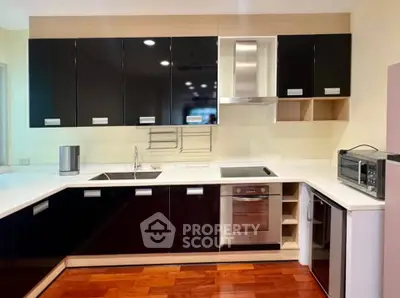 Modern kitchen with sleek black cabinets, built-in oven, and stylish open layout.