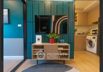 Modern living room with stylish TV unit and open kitchen featuring washing machine.