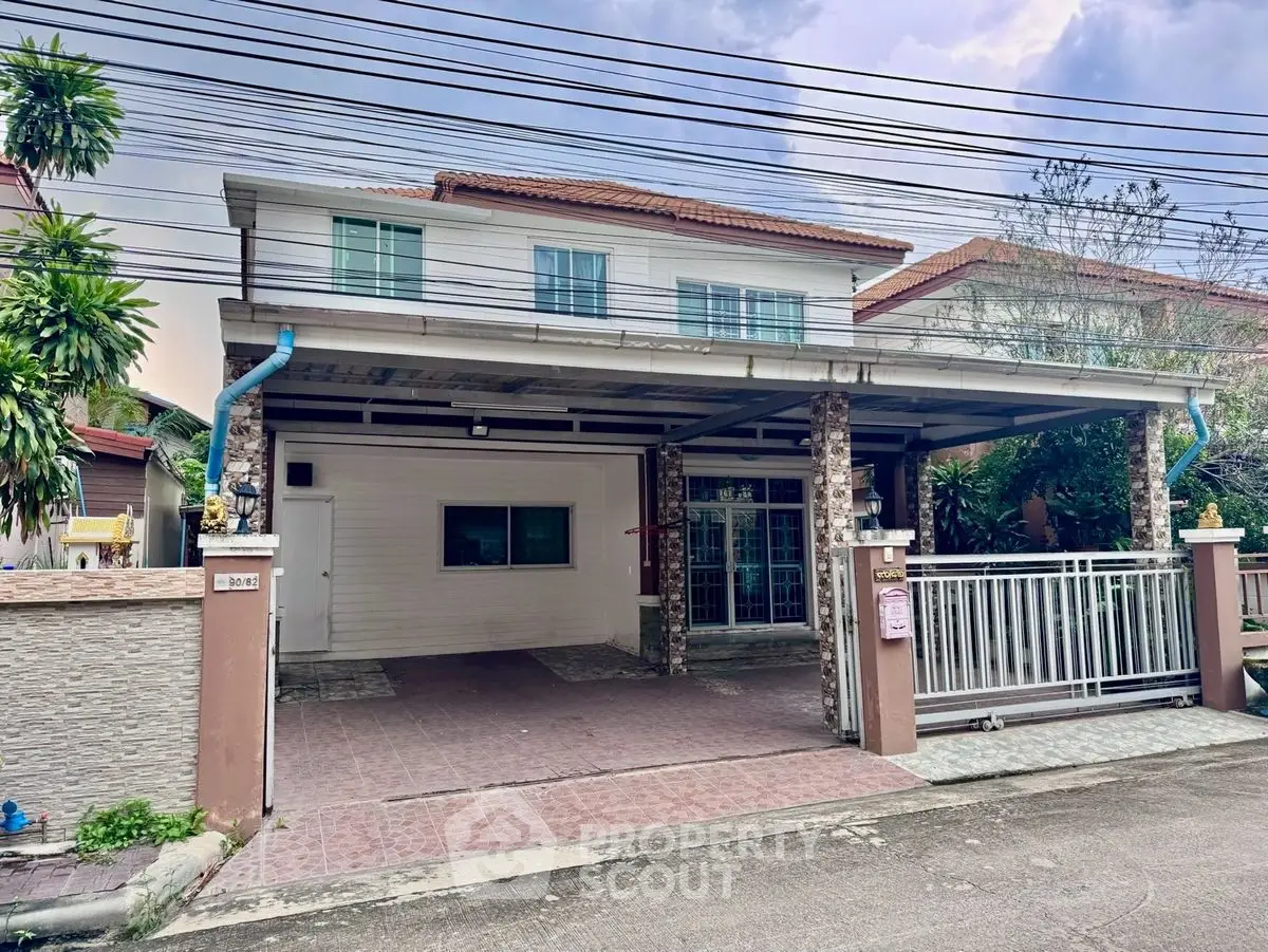 Charming two-story house with spacious carport and gated entrance in a serene neighborhood.