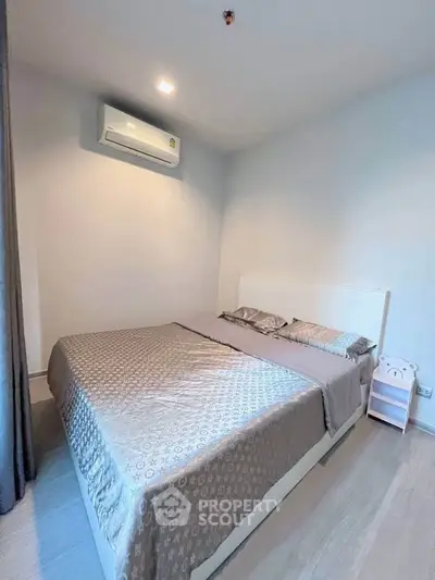 Cozy bedroom with modern air conditioning and stylish bedding in a serene apartment setting.