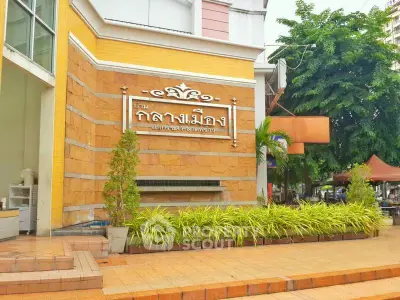 Charming building entrance with lush greenery and elegant signage.