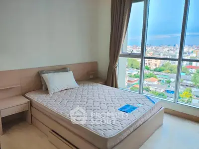 Spacious bedroom with large window offering stunning city view