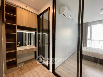 Modern bedroom with glass partition and wooden flooring, featuring a built-in vanity and ample natural light.