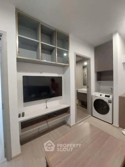 Modern living room with built-in TV unit and washing machine in compact apartment.