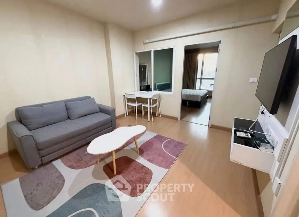 Modern living room with cozy sofa, stylish rug, and wall-mounted TV in a contemporary apartment.