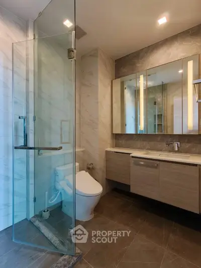 Modern bathroom with glass shower and elegant vanity in luxury apartment