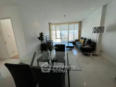 Modern living room with glass dining table and city view, featuring sleek furniture and stylish decor.