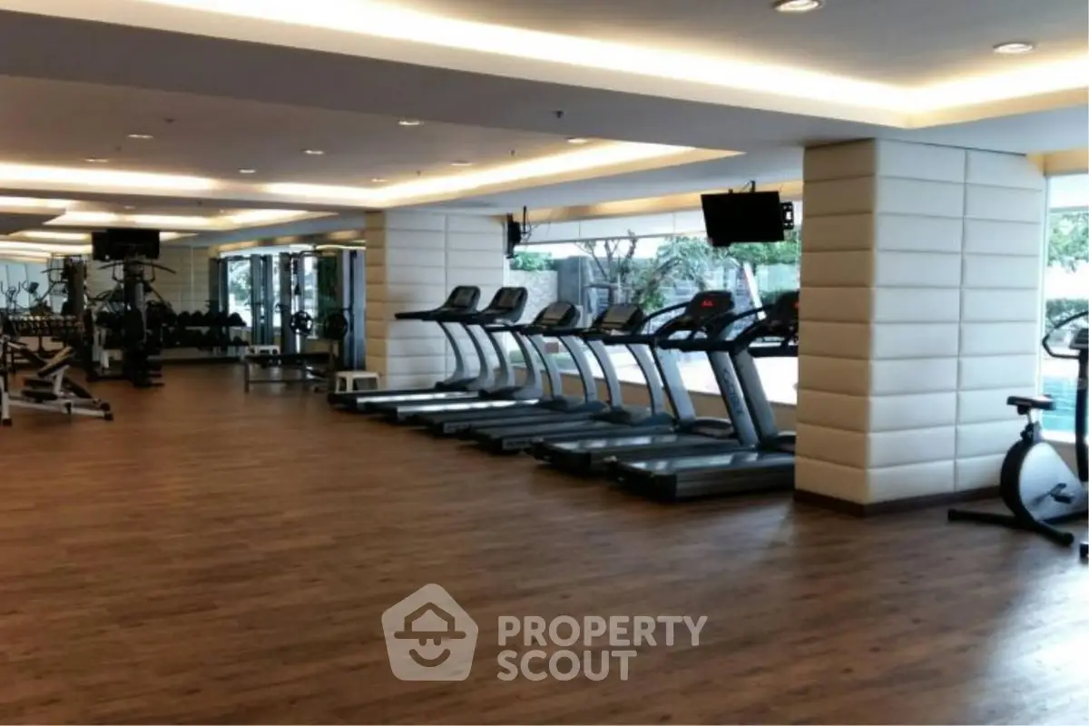 Spacious modern gym with treadmills and exercise equipment in luxury apartment complex.
