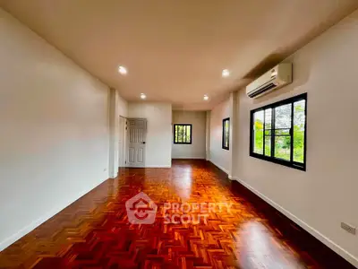 Spacious living room with hardwood floors and large windows offering natural light.