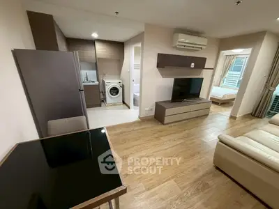 Modern apartment interior with open layout, featuring a cozy living room, kitchen, and bedroom view.