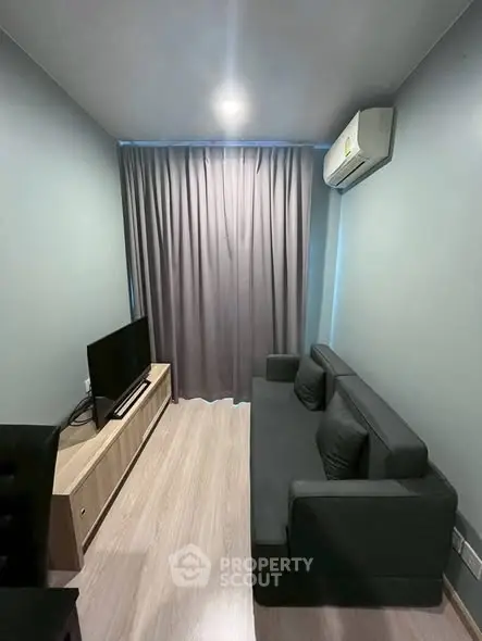 Cozy living room with modern sofa and entertainment unit, featuring sleek air conditioning and elegant curtains.