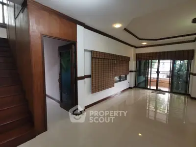 Spacious living room with wooden accents and large windows leading to a balcony.