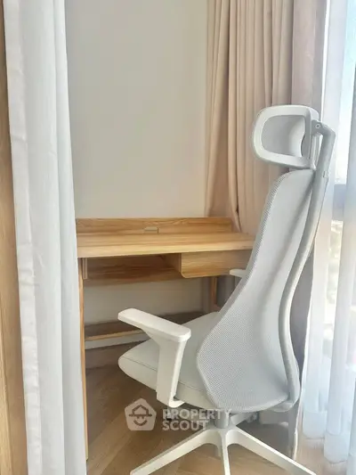 Modern study nook with ergonomic chair and wooden desk by a sunlit window, perfect for productivity.
