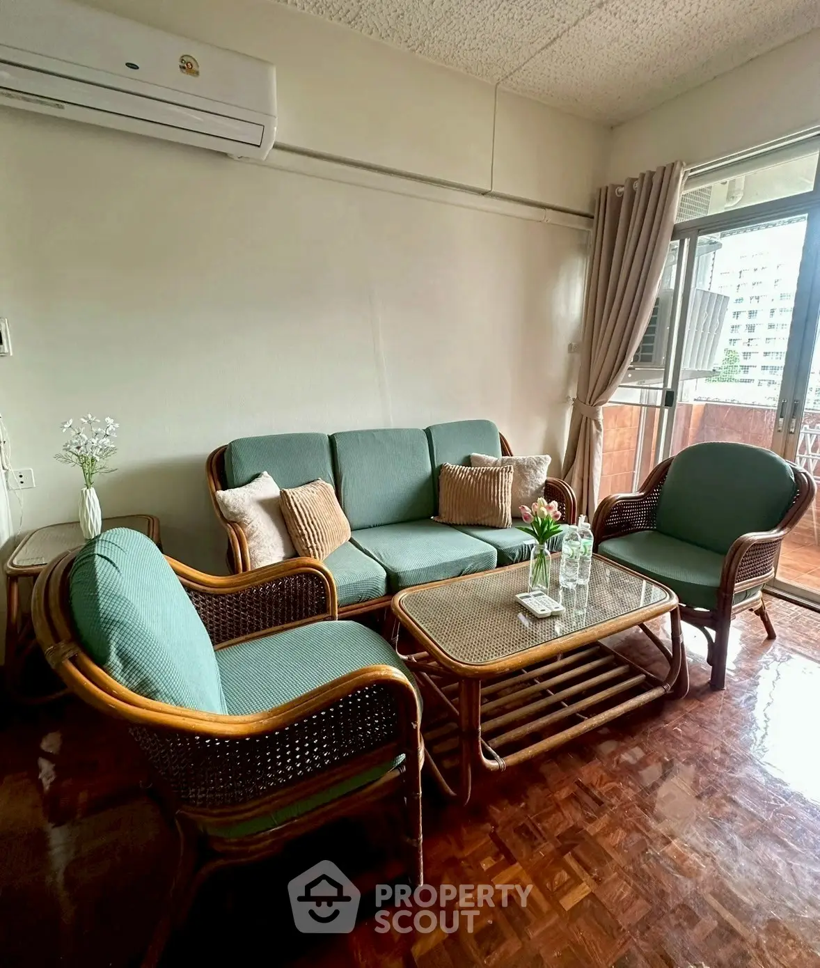 Charming living room with cozy rattan furniture and balcony access, perfect for relaxation.